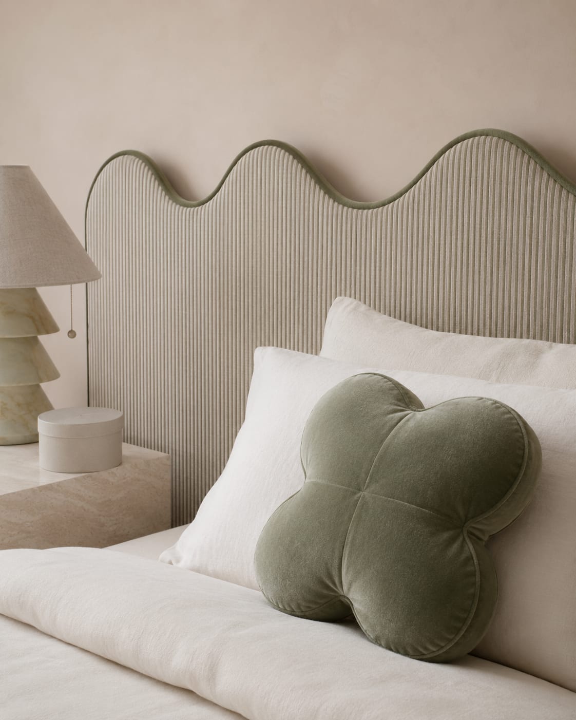 Scalloped bed headboard in ribbed sage bouclé with velvet piping, styled with a clover-shaped velvet pillow