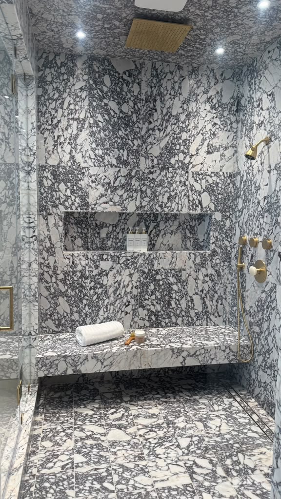 Steam shower fully clad in dark veined marble slab